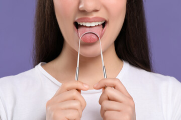 Woman brushing her tongue with cleaner on violet background, closeup