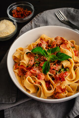 Pappardelle Pasta in Tomato Cream Sauce with Peas and Prosciutto: Italian-style wide noodles in a pasta bowl with basil and grated parmesan cheese