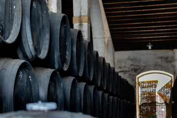 Black wine barrels with wine in winery warehouse