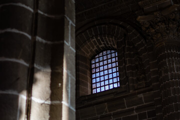Window with metal bars of Catholic cathedral with blurred sunlight in foreground