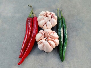 curly red chilies, garlic and curly green chilies isolated on a gray background. spices.
