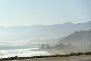 an empty roadway with mountains and the ocean in the background