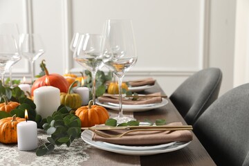 Beautiful autumn table setting. Plates, cutlery, glasses, pumpkins and floral decor