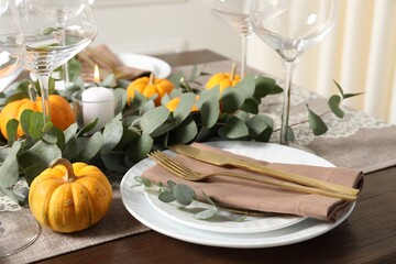 Beautiful autumn table setting. Plates, cutlery, glasses, pumpkins and floral decor