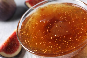 Glass bowl with tasty fig jam on table, closeup