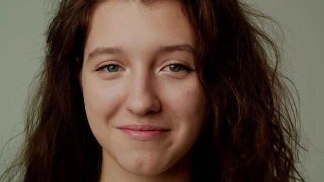 A positive young attractive actress or model poses for a fashionable glossy magazine. A girl smiles modestly in response to a compliment or good news. The concept of natural beauty. Looks at camera