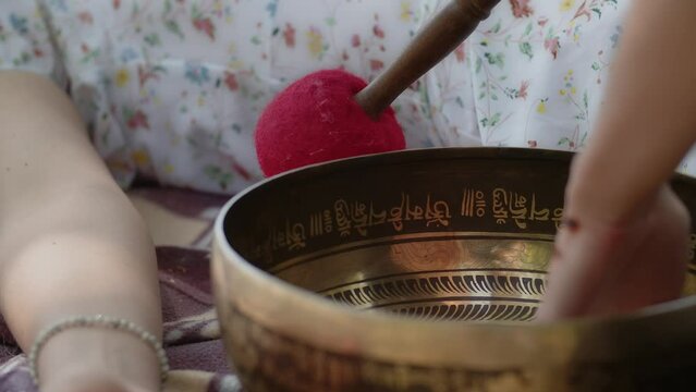A shaman girl performs a cleansing ritual for prosperity, longevity, fulfillment of desires, rid of failures and illness. A healer uses tibetan singing brass bowl and handmade wand near woman patient