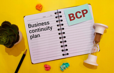a black calculator, a pen, and a notebook with the text BCP Business Continuity Plan