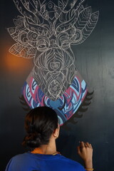 Woman drawing a picture on the wall with a brush. Beautiful model woman making artistic drawing on the wall