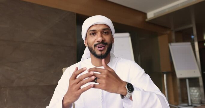 Webcam view 25s Sudanese Arabian businessman in traditional attire sit in office staring at camera, make video call, virtual meeting by business with partners. Record, blog, negotiates use modern tech