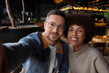 International dating. Happy couple taking selfie in cafe