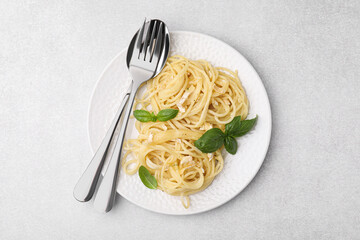 Delicious pasta with brie cheese and basil leaves on light grey table, top view