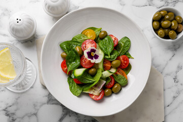 Delicious salad with vegetables and olives served on white marble table, flat lay