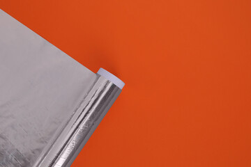 Roll of aluminum foil on orange background, top view. Space for text - obrazy, fototapety, plakaty