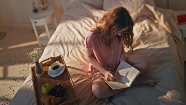 Pensive woman writing diary at home. Relaxed teenager dreaming sharing creative