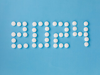 2024 Happy New Year banner for health care and medical concept. Number 2024 made from tablets on blue background. View from above flat lay. Medical concept