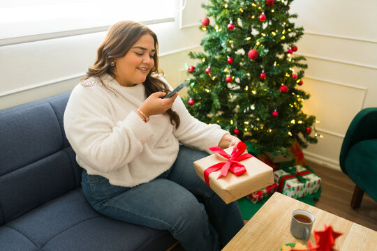 Happy woman excited about chrismtas gifts taking photos for social media