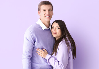 Happy young couple hugging on lilac background