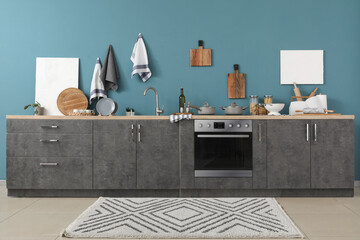 Interior of modern kitchen with grey counters, cutting boards, electric stove and oven
