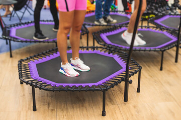 Trampoline fitness jumping training, group of young fit women in sportswear jump on trampolines,...