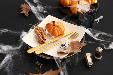 Halloween table setting with tasty pumpkin shaped bun and web on dark background, closeup