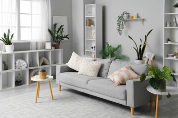 Interior of living room with grey sofa and shelf units