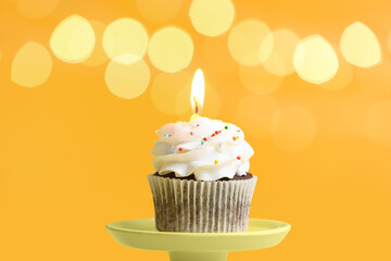 Stand with tasty Birthday cupcake against blurred lights
