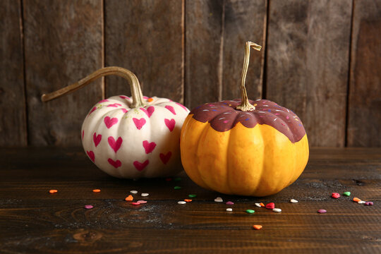 Painted Halloween pumpkins with hearts and chocolate topping on wooden background