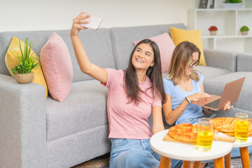 Students taking a selfie while eating pizza together at home