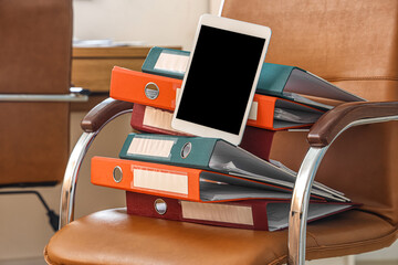 Document folders with tablet computer on chair in office, closeup