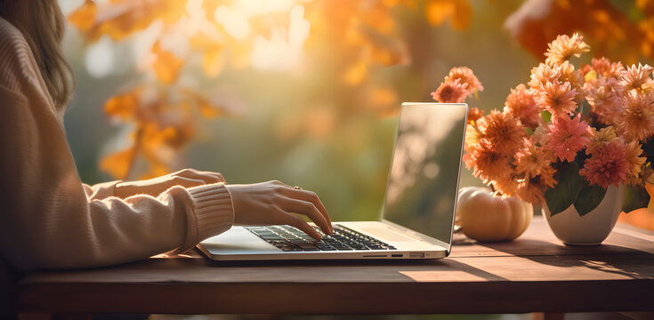 young woman hand using laptop in the park, using laptop computer while spending sunny autumn day outdoors