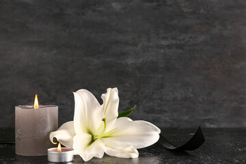 Beautiful lily flower and burning candle on black table