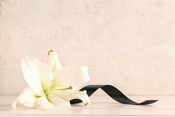 Beautiful lily with black ribbon on beige background