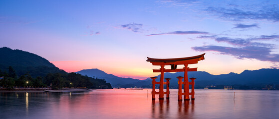 Panoramic view of Itsukushima Shrine's torii gate at Miyajima in Hiroshima at magic hour. - obrazy, fototapety, plakaty