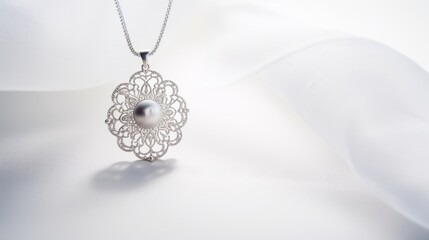 A silver necklace with a round filigree pendant and a pearl on a white fabric. The pendant is intricate and elegant. The fabric is silky and soft.