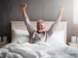 Happy old man in nightwear in bed feel good, stretching her arms muscles after sleep