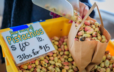 Fresh raw pistachio nuts, fruit to be peeled and dried sold in bulk at a farmers market in San...