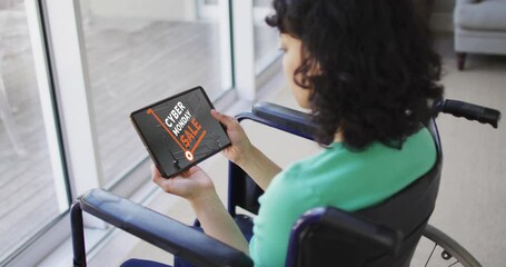 Biracial woman sitting in wheelchair using tablet, online shopping on cyber monday, slow motion - Powered by Adobe