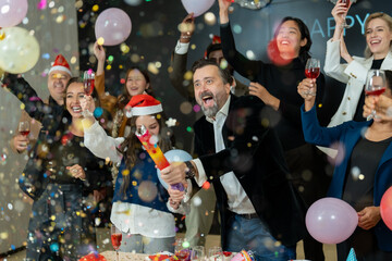 Group of office workers celebrate Christmas and New Year by dancing and drinking wine. Group of international friends and boss dancing with employees.
