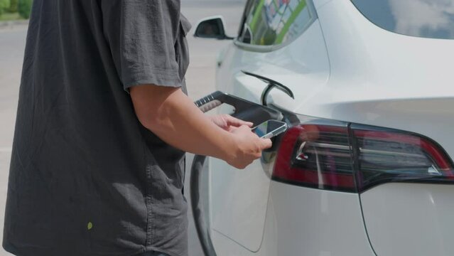 Business man use smartphone to use ev car charge outdoor station vacation trip