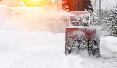 snowblower removes snow, a man cleans the yard outside