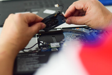 computer technician laptop motherboard repair technician Removing a fan from the computer...