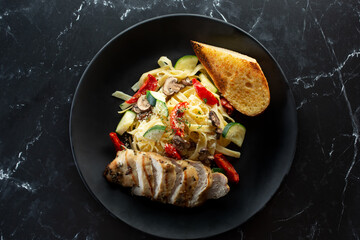 A top down view of a plate of chicken pasta primavera.