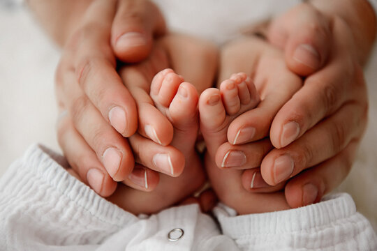 Baby's feet in in the hands of parents. Closeup photo. Happy Family concept. 