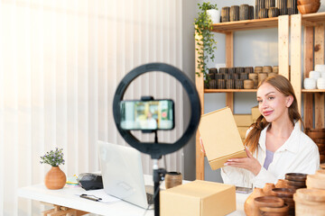 Caucasian casual business ownership record live video by smartphone with selfie ring light while review feature handmade product and package delivery to customer at home office