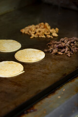 A view of the preparation of warming up street tacos on a griddle.