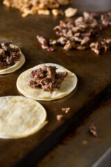 A view of the preparation of warming up street tacos on a griddle.