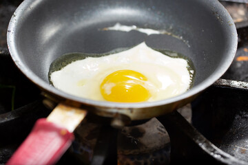 A view of an egg frying in a non-stick skillet.