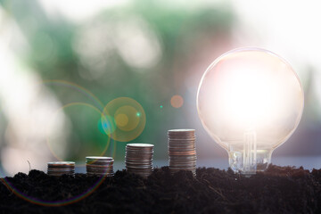 Coin of growing up and light bulb on the soil. Saving money and saving energy concept. concept of a growing business - obrazy, fototapety, plakaty