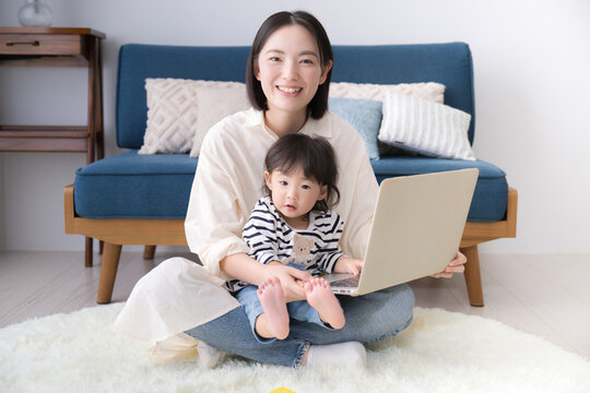 パソコンを一緒に見て動画などを見る笑顔の親子 親子でカメラ目線の正面 教育などのイメージにも